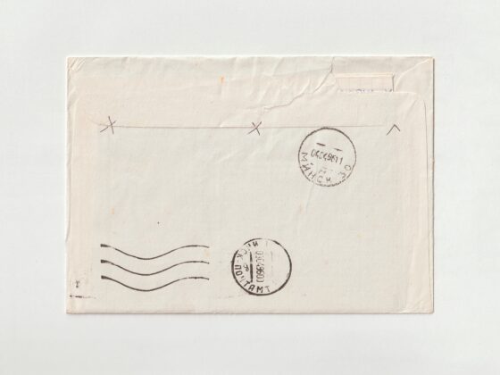 Close-up of a worn envelope edge with a circular postmark and partial postage stamp, showing creases and wear.