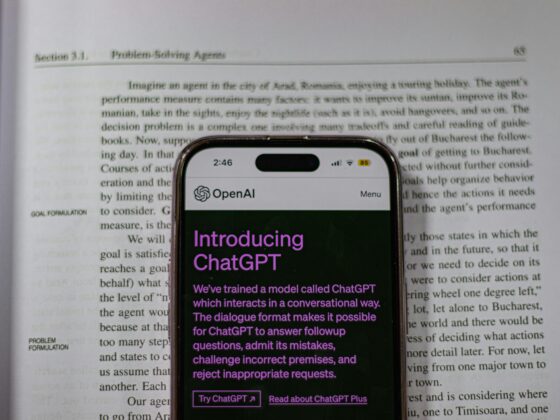 Smartphone screen showing the OpenAI ChatGPT app with a purple 'Introducing ChatGPT' headline over a printed article background.