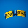 Yellow and blue parachute in a clear blue sky, with the word 'FOOD SEAL' on the panels visible from below.