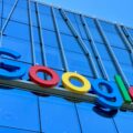 Close-up of a colorful Google logo mounted on a blue glass building exterior.