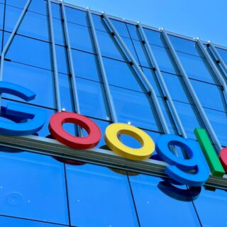 Close-up of a colorful Google logo mounted on a blue glass building exterior.