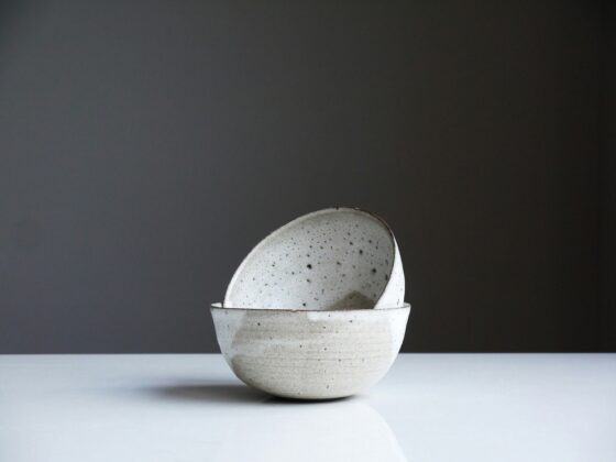 Stack of speckled ceramic bowls stacked on a white surface against a dark gray background.