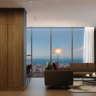 Modern living room with wooden cabinet divider, brown sofa, and a panoramic city and sea view through floor-to-ceiling windows.