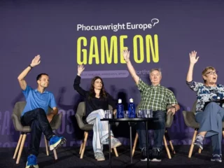 Panel of four speakers on a stage at Phocuswright Europe, waving their hands during a 'GAME ON' session on a purple backdrop.