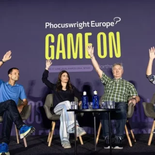 Panel of four speakers on a stage at Phocuswright Europe, waving their hands during a 'GAME ON' session on a purple backdrop.
