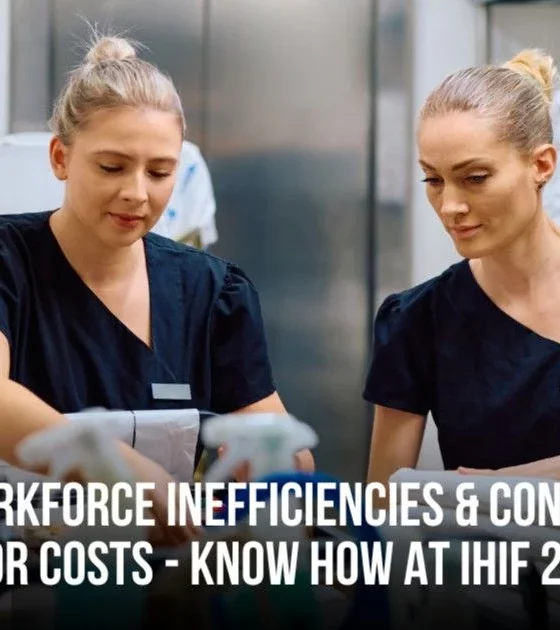 Two female healthcare workers in dark scrubs work at a station, with a UNIFOCUS logo in the top-left and a banner about reducing workforce inefficiencies for IHF 2025.