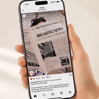 Hand holding an iPhone displaying an Instagram post with a newspaper front page that reads “BREAKING NEWS” and “LA CONCHA TURNS 100.”] ,