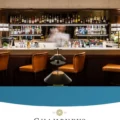Bar interior with liquor shelves and four orange leather stools along a white counter; a blurred bartender in the center.