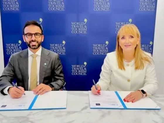 Two professionals sign documents at a signing table, with a blue World Travel & Tourism Council backdrop behind them.