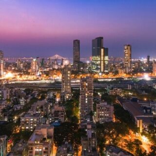 Aerial view of a city at twilight with illuminated buildings and a pink-purple sky at dusk.”,