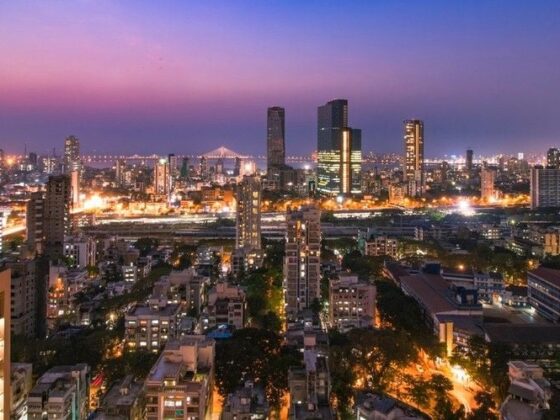 Aerial view of a city at twilight with illuminated buildings and a pink-purple sky at dusk.”,