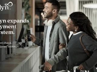 Cendyn logo with a man and woman at a service counter, travelers with luggage, conveying a payment-ecosystem promo.