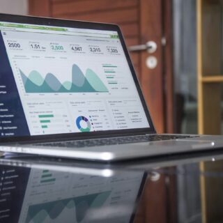 Laptop screen displaying a data analytics dashboard with charts and metrics on a dark sidebar UI
