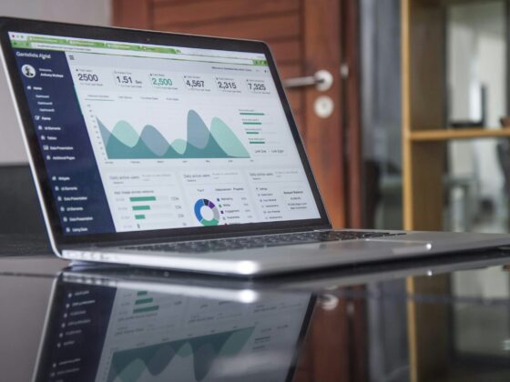 Laptop screen displaying a data analytics dashboard with charts and metrics on a dark sidebar UI