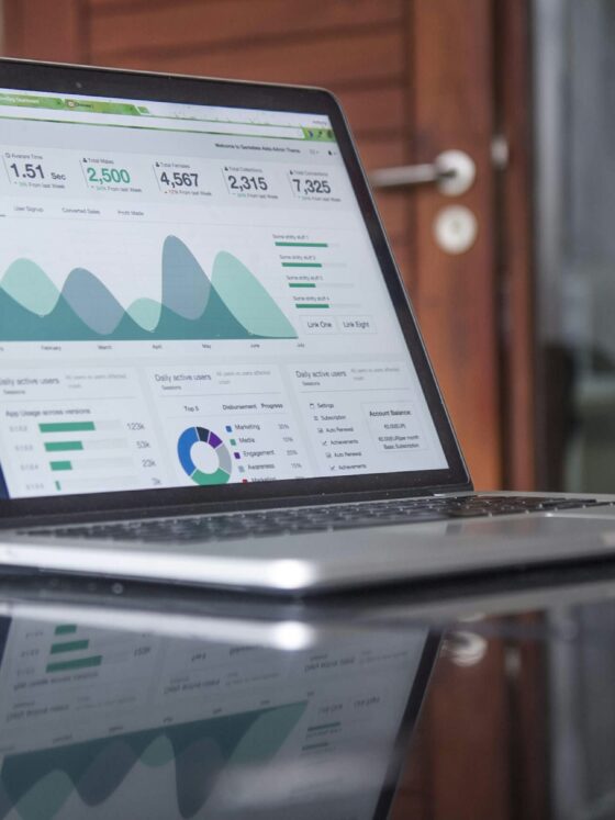Laptop screen displaying a data analytics dashboard with charts and metrics on a dark sidebar UI
