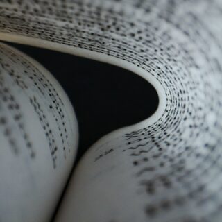 Close-up of a rolled newspaper page with black printed text visible on the inner sheet, curling inward.