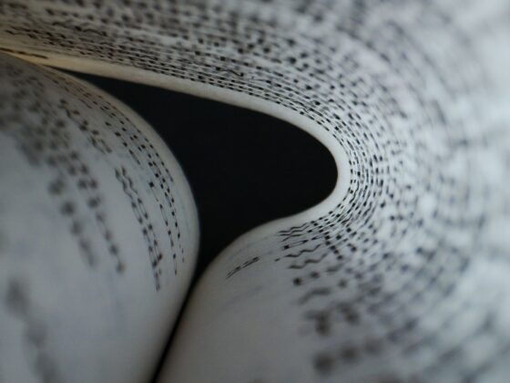 Close-up of a rolled newspaper page with black printed text visible on the inner sheet, curling inward.