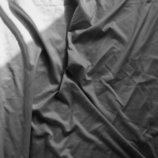 Close-up of black fabric with prominent folds and shadows in grayscale.