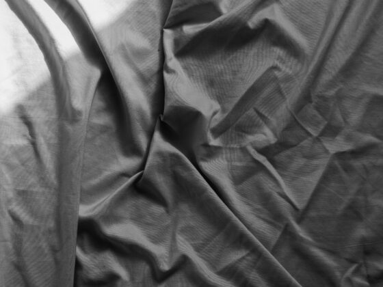 Close-up of black fabric with prominent folds and shadows in grayscale.