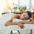 Woman receiving a relaxing massage on a spa table, eyes closed and head resting on a towel-lined pillow
