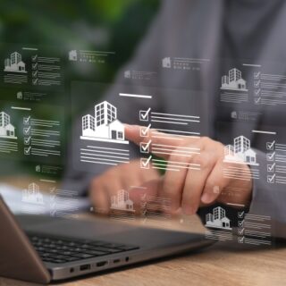 Person typing on a laptop with floating holographic building icons and checklists.