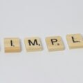 Wooden Scrabble-style tiles spell the word 'SIMPLE' in a row on a light background.