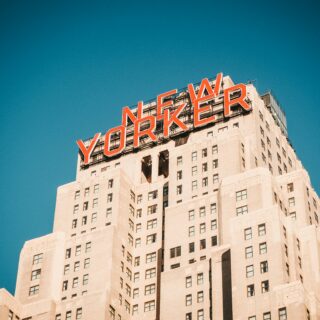 Beige high-rise building with a large red YORKER sign on the roof against a clear blue sky.